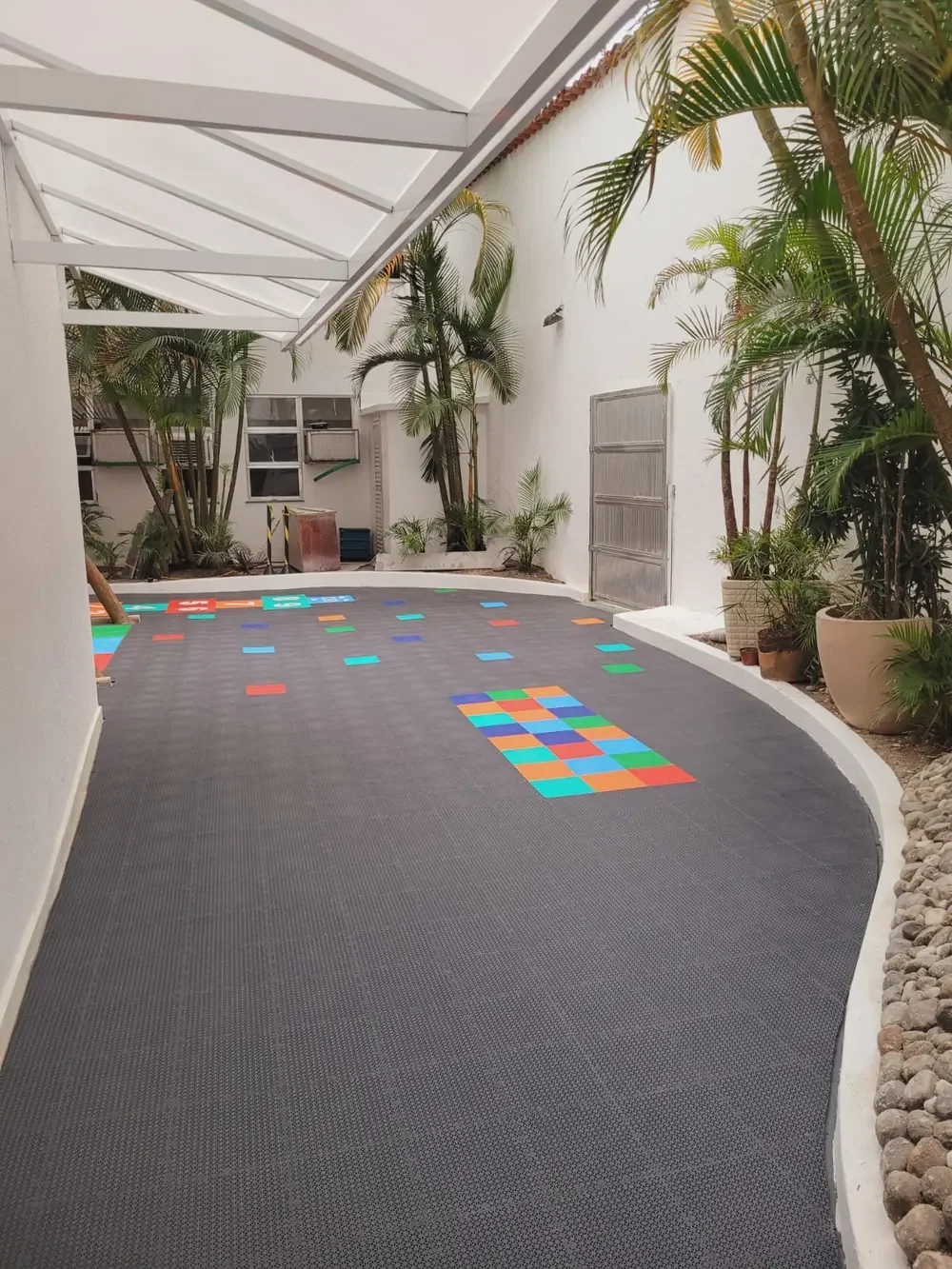 Pátio coberto com piso modular escuro e detalhes coloridos